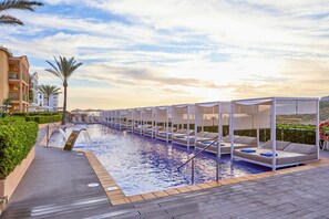 Un área de piscina con sillones de descanso y una terraza de madera.