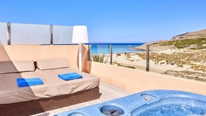 Un balcó amb llit, un banyera d'hidromassatge i vistes a la platja.