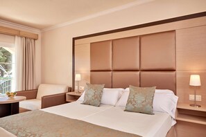 A hotel room with a large bed, two bedside tables, a chair, and a window with curtains. - Zafiro Cala Mesquida (Capdepera)