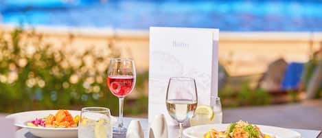 A dining table with two plates of food, two glasses of water, and a menu card.