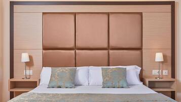 A hotel room with a large bed, two bedside tables with lamps, and a headboard with a padded design.