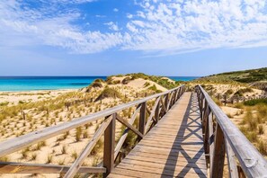 A wooden boardwalk leading to a beach with dunes and a clear blue sky. - Zafiro Cala Mesquida (Capdepera)