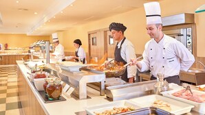 Un aparador tipus bufet amb diferents espais de cuina, cuiners preparant aliments i una gran varietat de plats exposats.