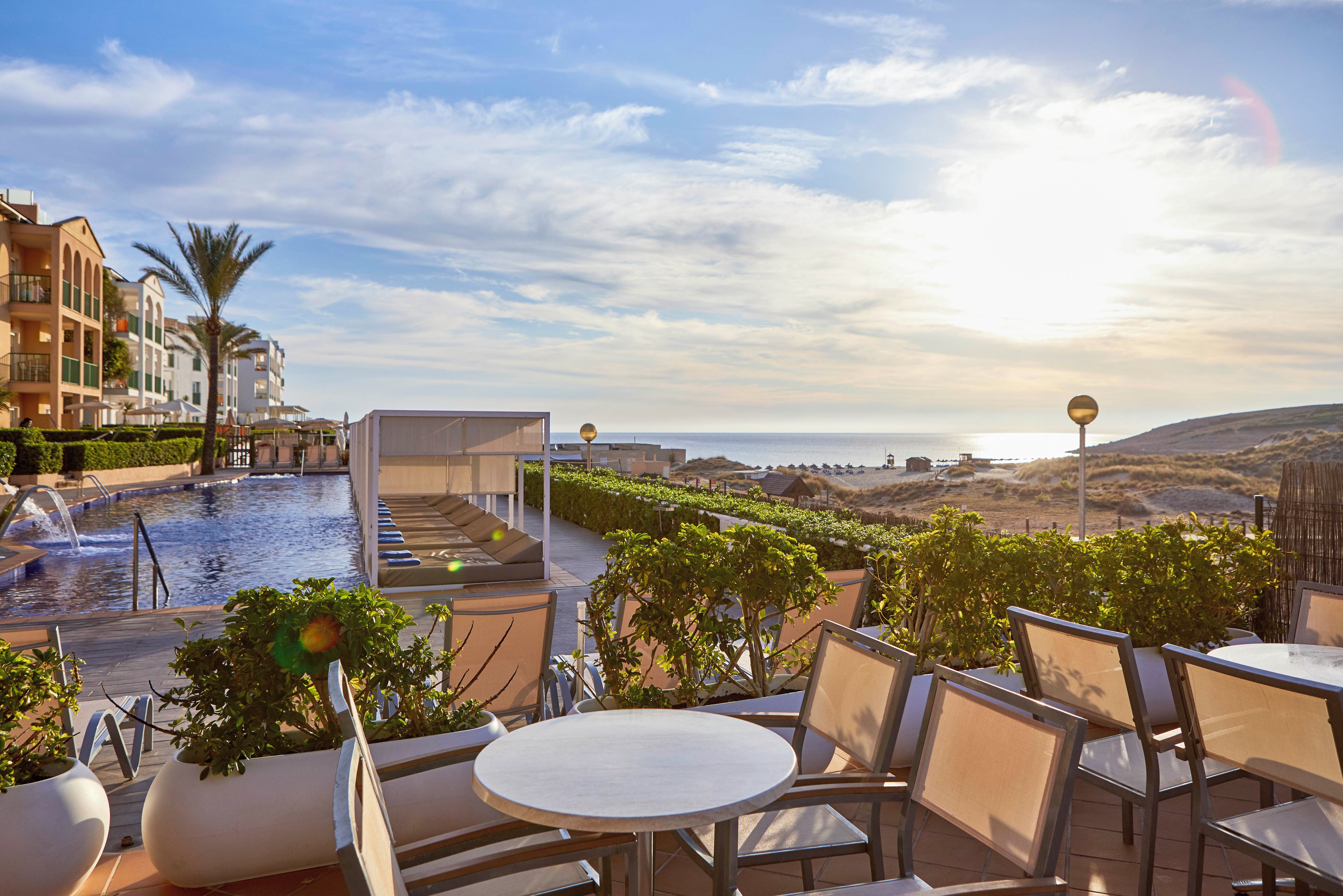 A rooftop pool area with lounge chairs and a view of the ocean.