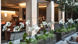 A modern indoor space with a seating area, planters with white orchids, and a view of the interior. - Grosvenor House Suites (London)