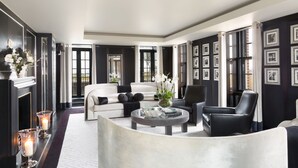 A modern living room with a white sofa, black armchairs, a glass coffee table, and a fireplace with candles. - Grosvenor House Suites (London)
