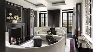 Een moderne woonkamer met een open haard, een bank, een salontafel en een groot raam met gordijnen.