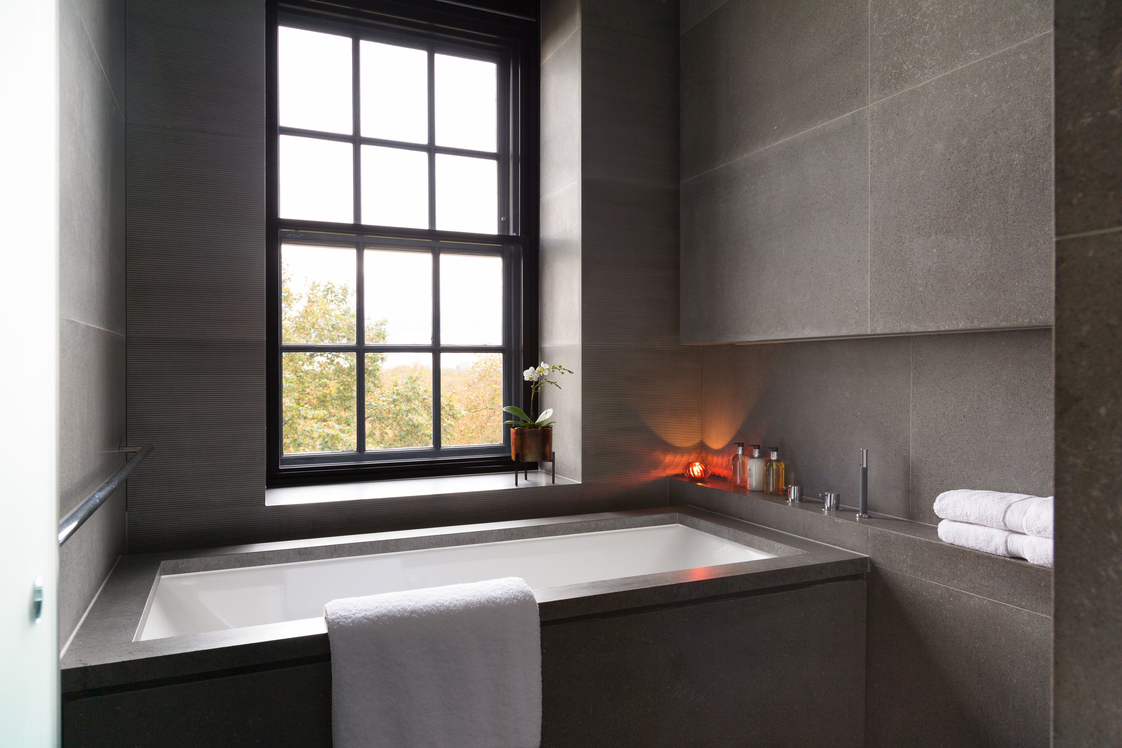 Ein modernes Badezimmer mit einem großen Fenster, einer Badewanne und einem Handtuchhalter.