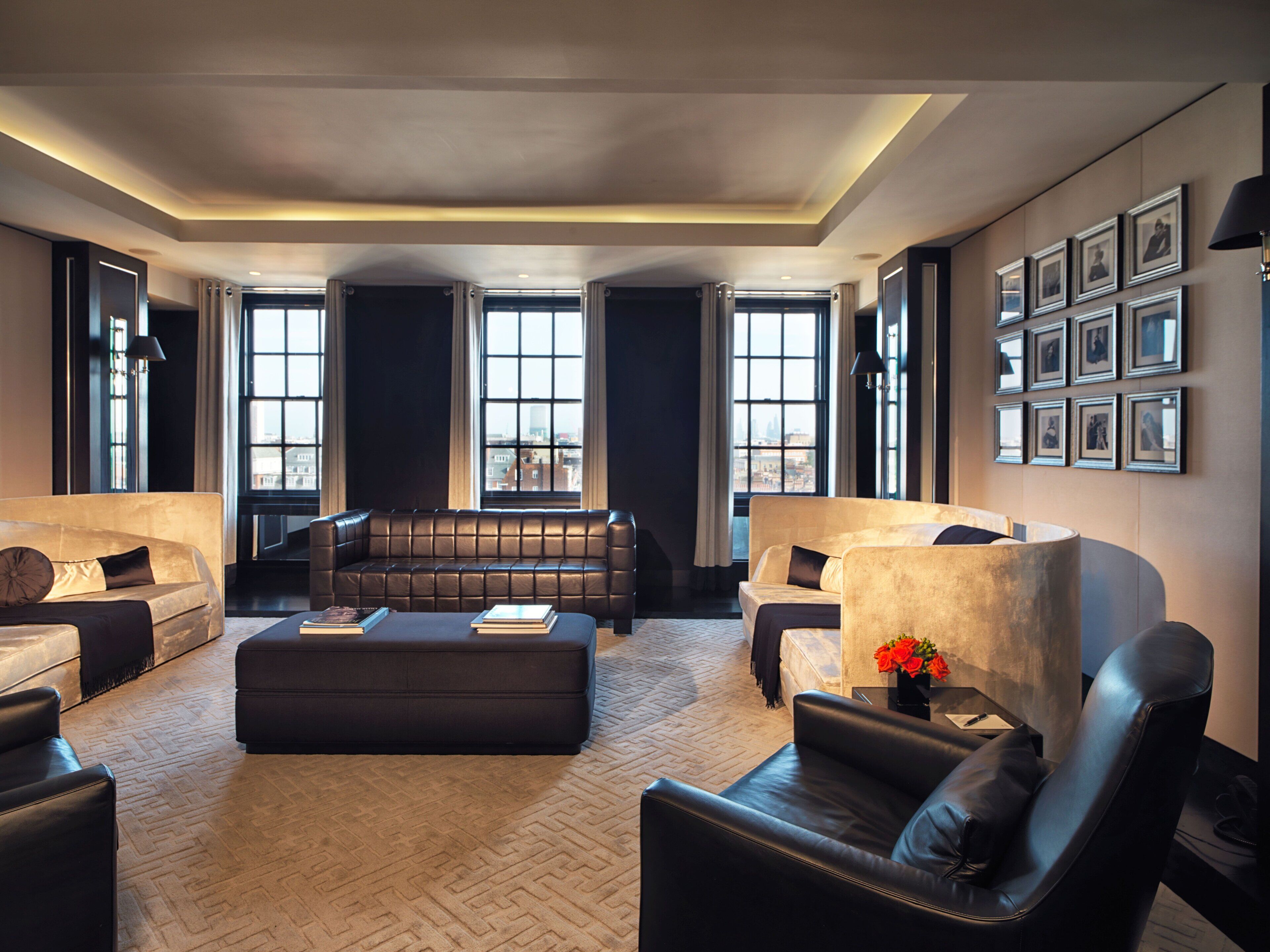 Ein modernes Wohnzimmer mit Ledersofas, einem Couchtisch und großen Fenstern mit Blick auf die Stadt.