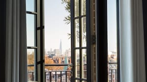 A view through a window with a metal railing, overlooking a cityscape with buildings and a tall skyscraper. - Grosvenor House Suites (London)