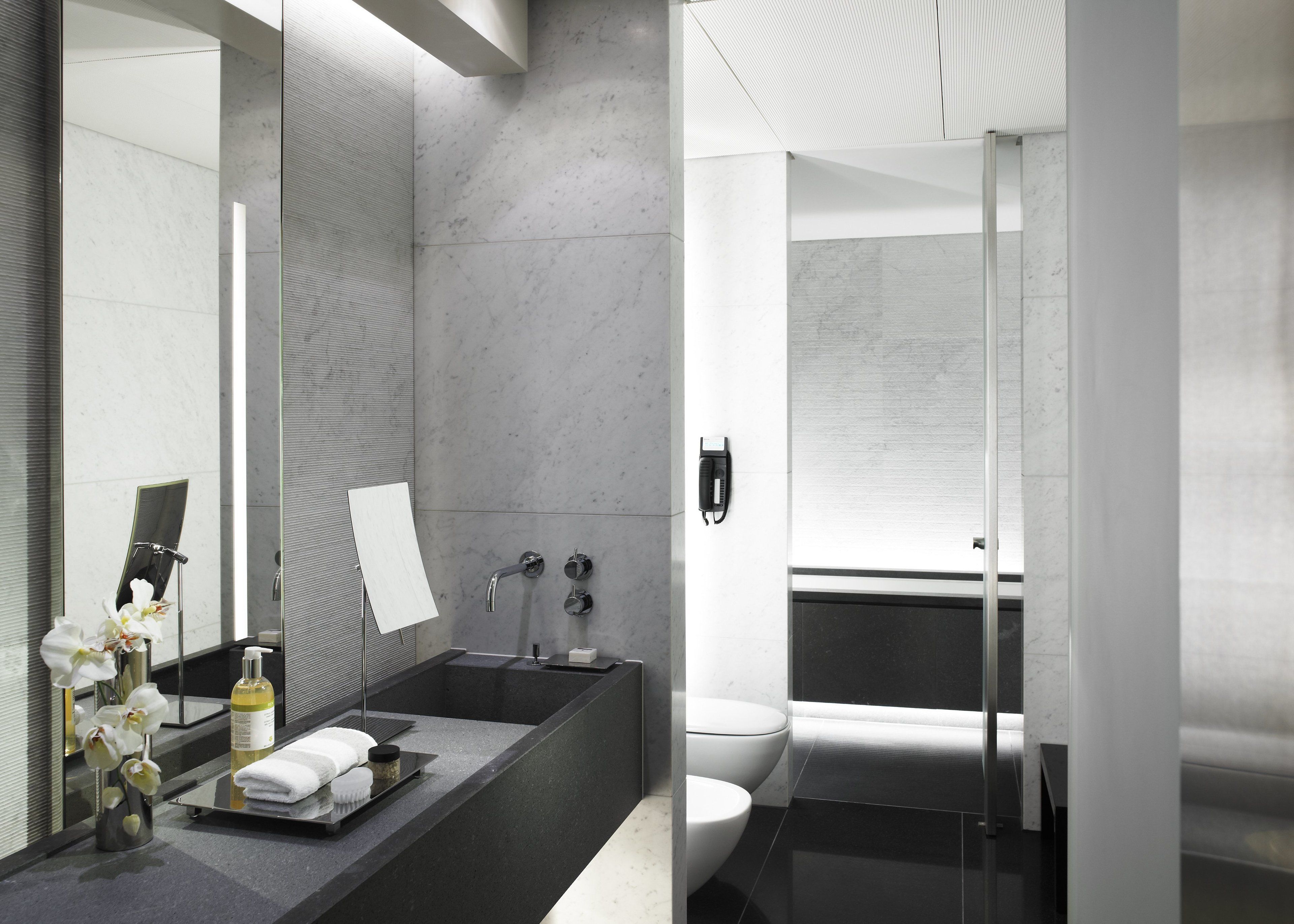 Un baño moderno con un espejo grande, una bañera y un inodoro.