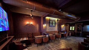 A restaurant interior with booths, tables, and a television screen. - Hotel Alka Residency (Thane)