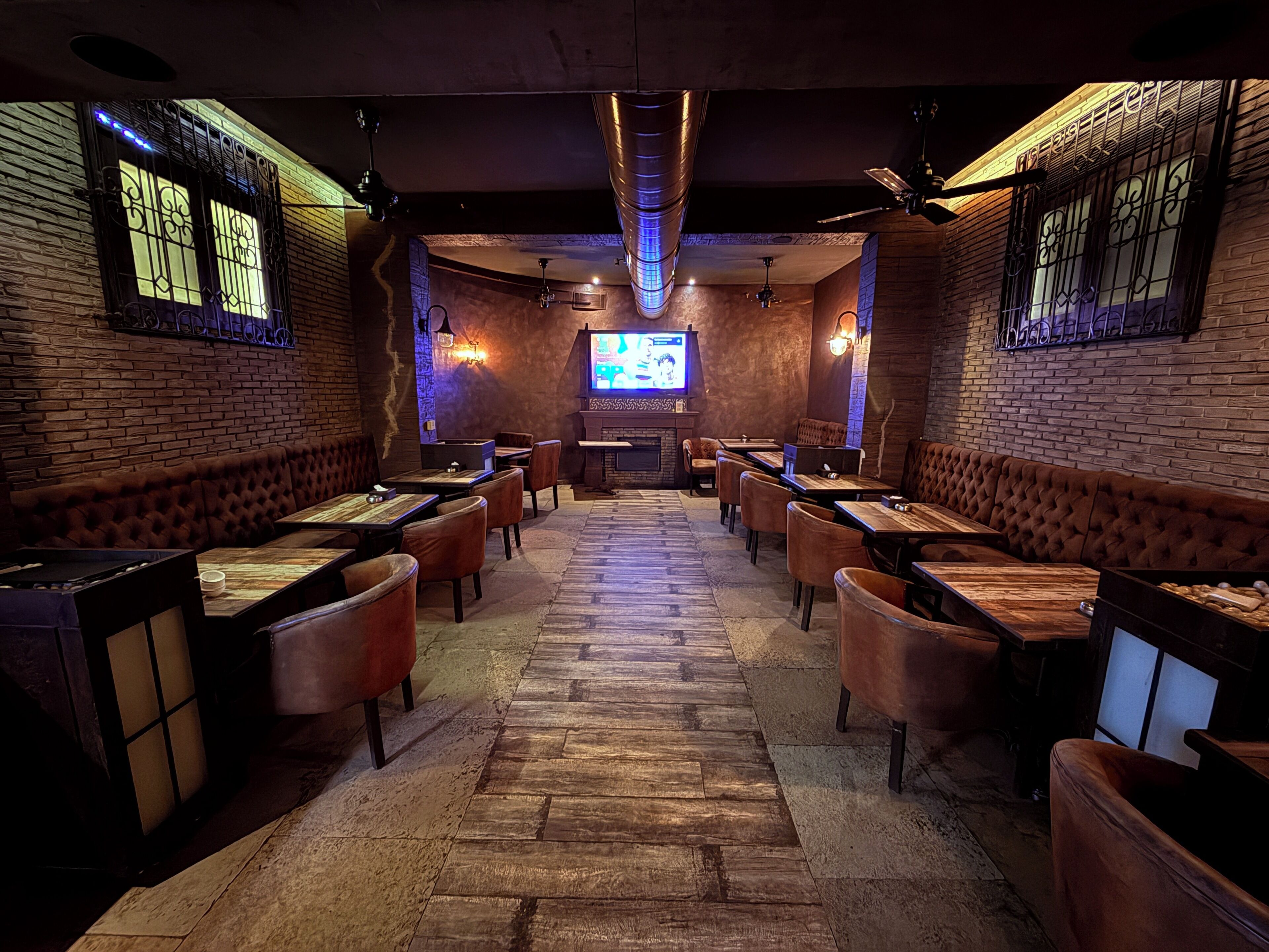 A restaurant with brick walls, wooden tables, and leather booths.