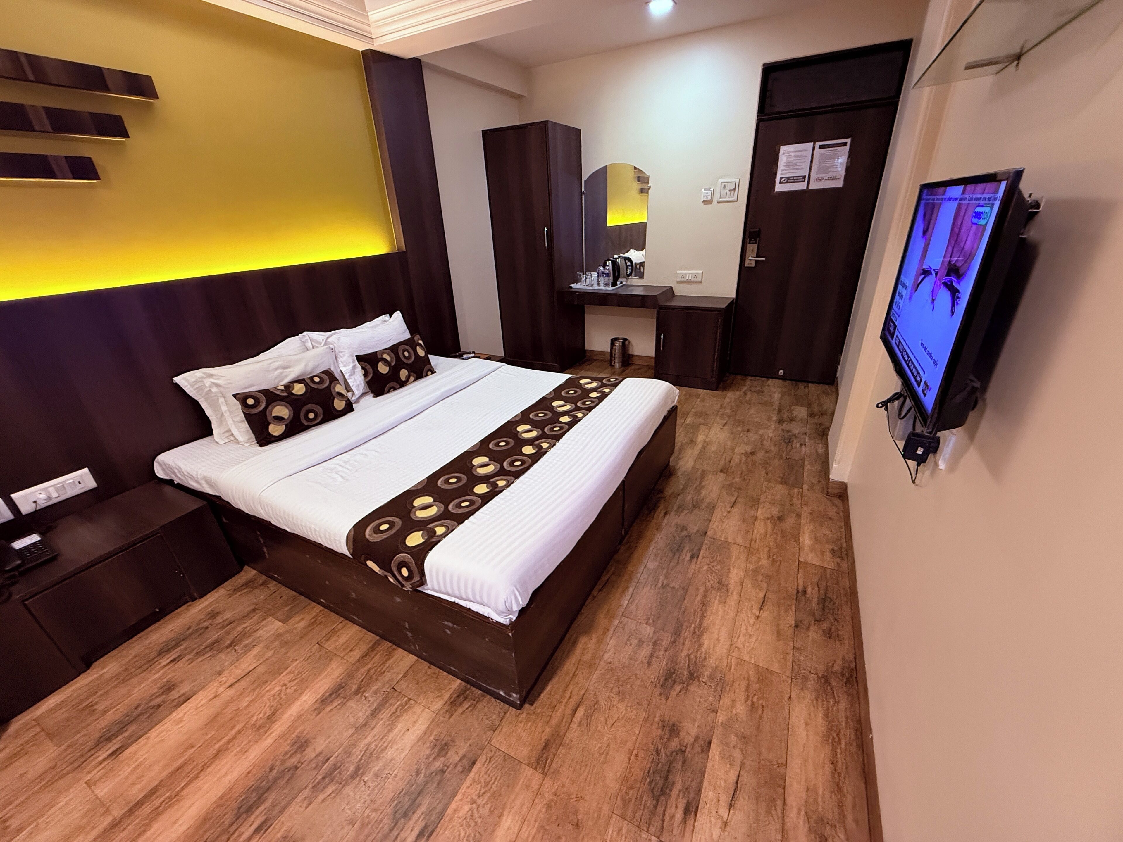 Ein Hotelzimmer mit Bett, Nachttisch, Fernseher und Schreibtisch mit Stuhl.