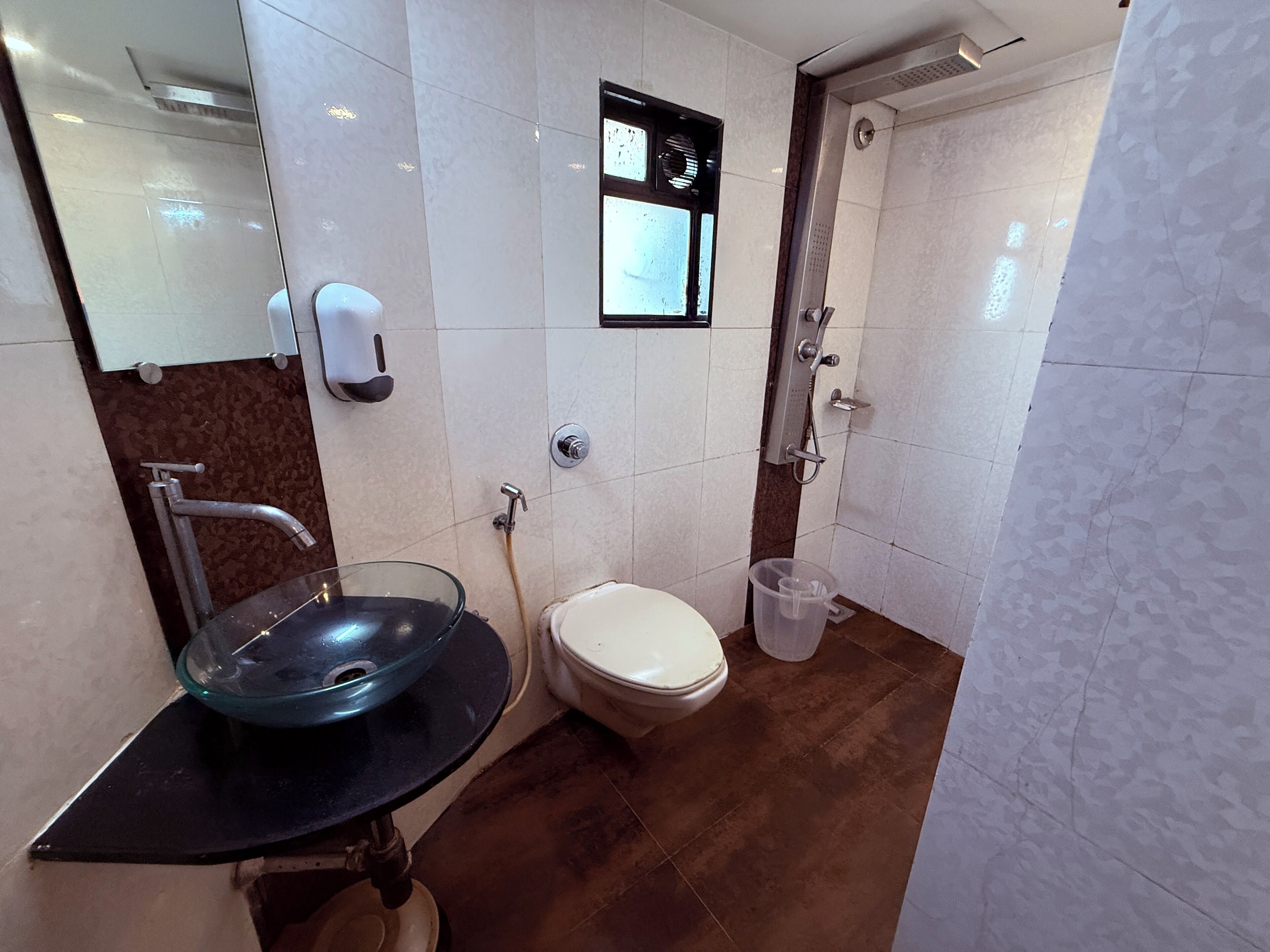 Baño con lavamanos de vidrio, inodoro y ducha.