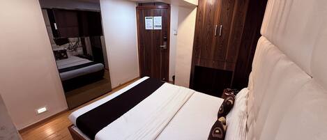 Un dormitorio con cama, armario de madera y una pequeña mesa de trabajo con lámpara.