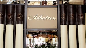 Et hotel lobby med et ternet gulv, et centralt siddeområde og et skilt med teksten "Allatross".
