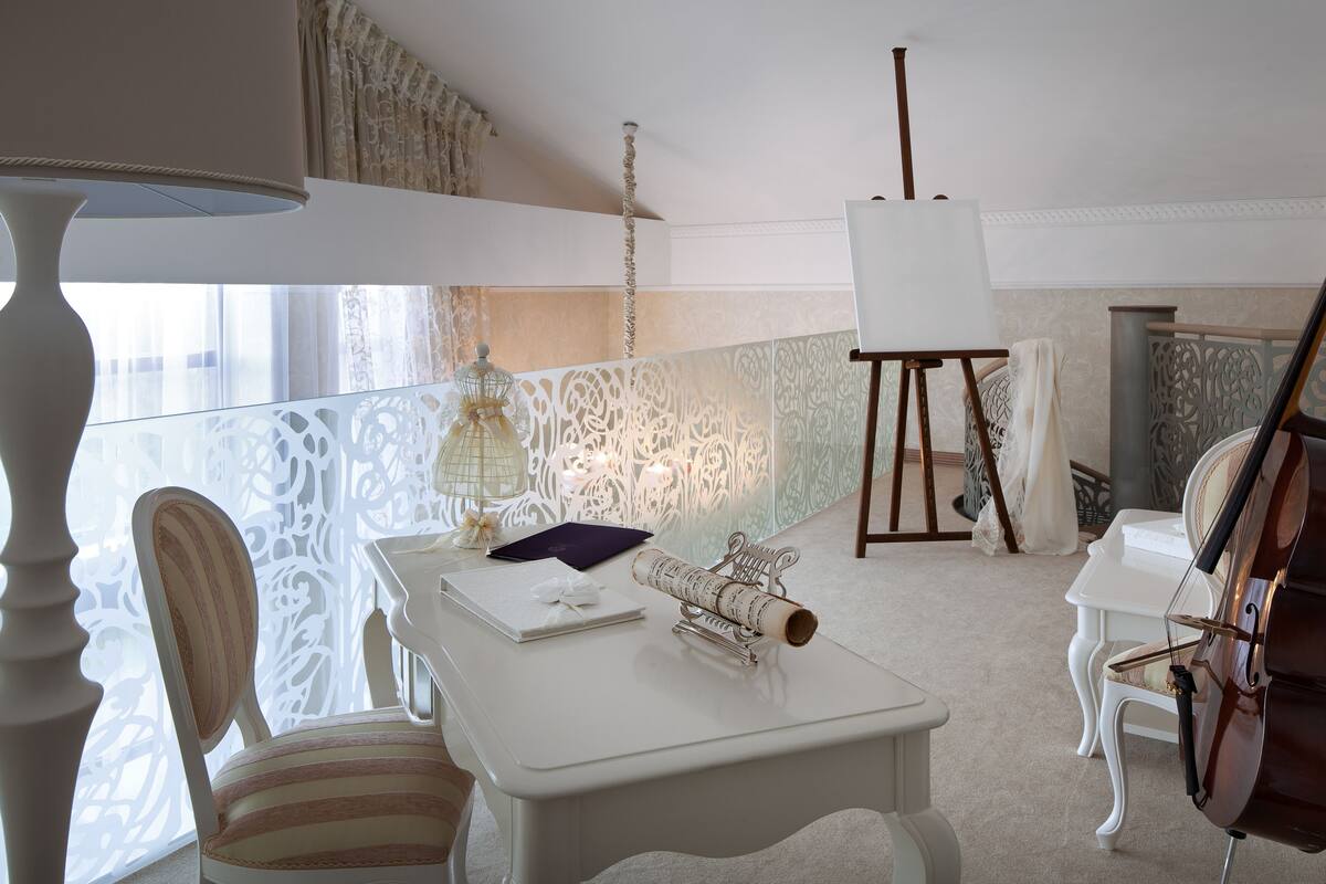 A room with a large window, a white table with a violin, a cello, and a lamp.
