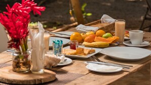 Mesa de madera con una comida dispuesta, que incluye frutas, pan y bebidas.