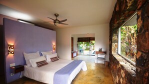 Un dormitorio con cama, mesitas de noche, ventilador de techo y vistas por la ventana.