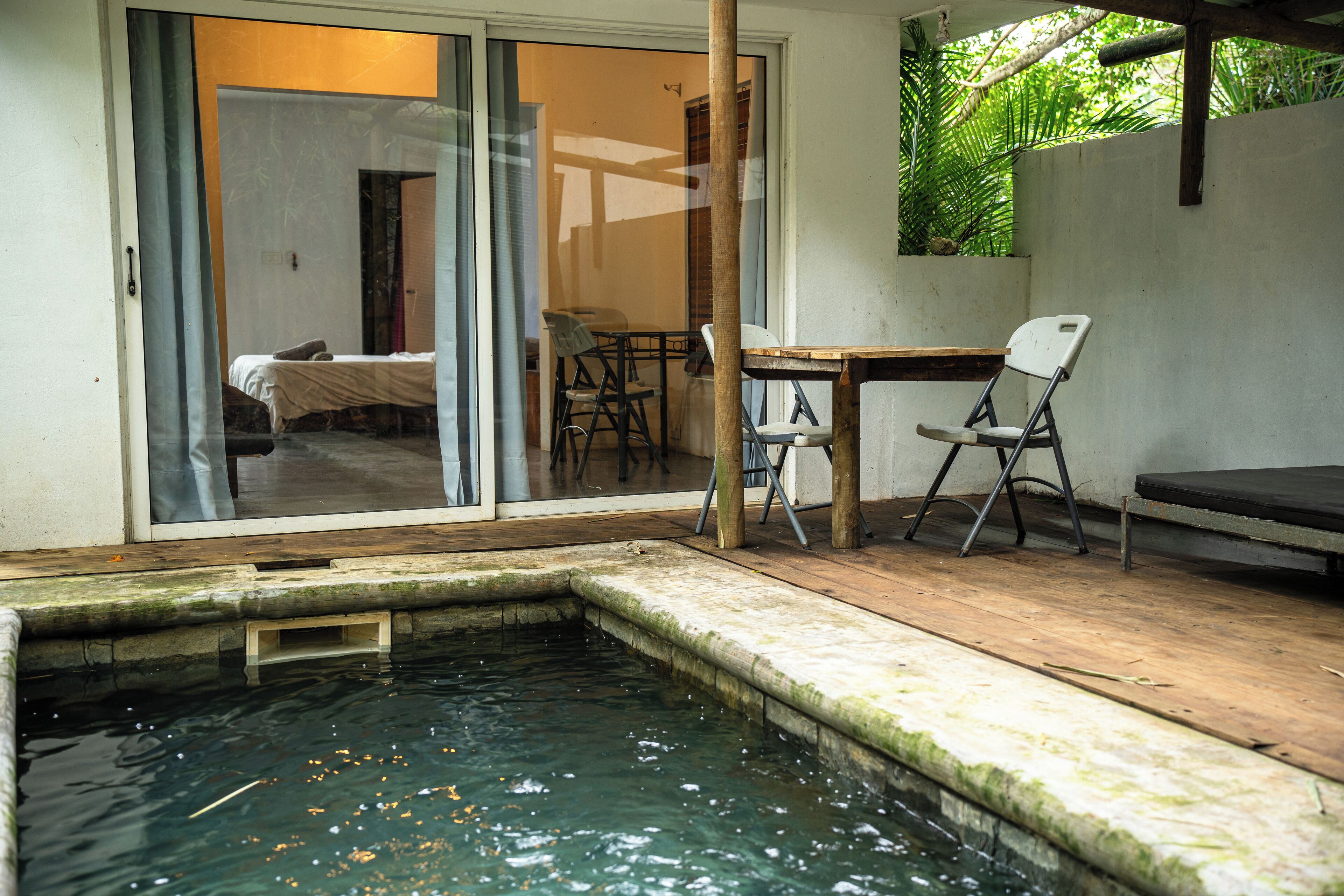 Una pequeña zona de piscina con cubierta de madera, una mesa y dos sillas.