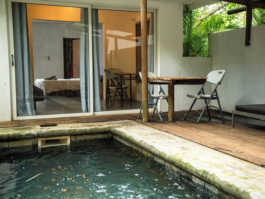 Una pequeña zona de piscina con cubierta de madera, una mesa y dos sillas.