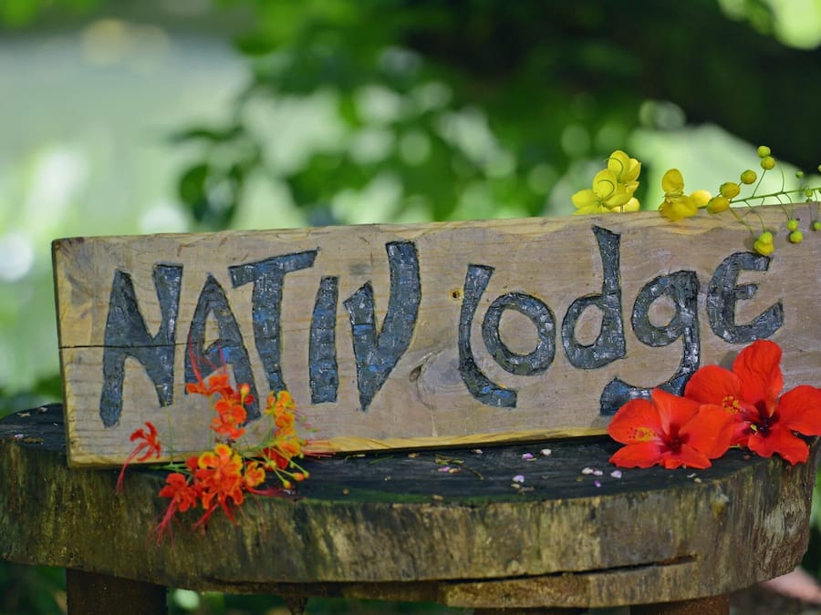 A wooden sign with the text "NATIV Lodge" surrounded by flowers.