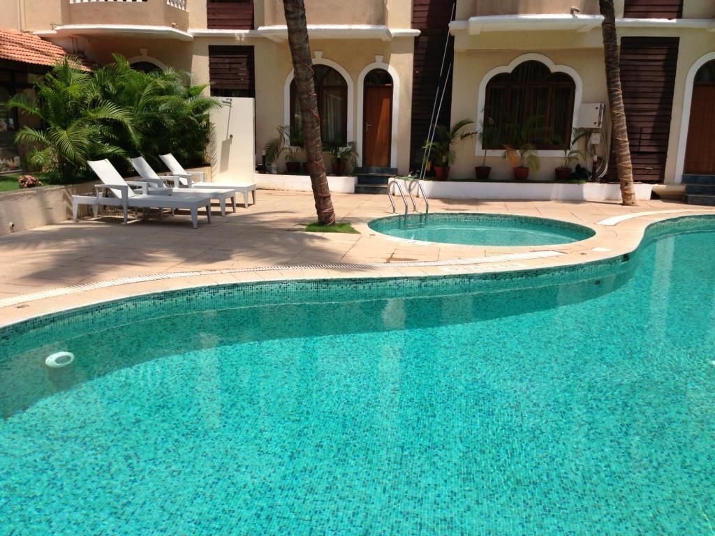 Una piscina con sillones de descanso y palmeras.