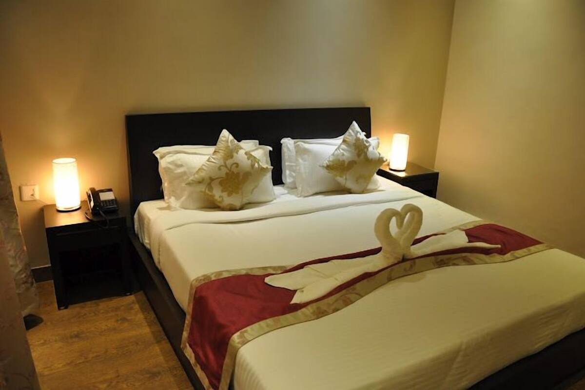 A hotel room with a bed, two bedside tables with lamps, and a decorative pillow arrangement.