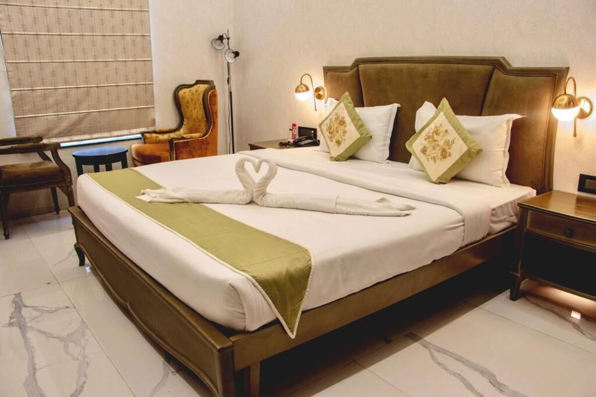 A neatly made bed with a green throw, a headboard, and decorative pillows.