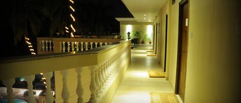 A corridor with a balustrade, a wooden door, and a potted plant.