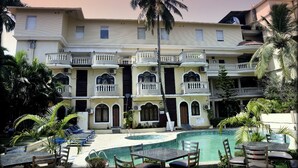 Un hotel con piscina, mobiliario exterior y palmeras.