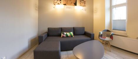 A modern living room with a sectional sofa, a small round table, and a decorative chair.