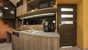 A modern kitchen with a built-in island, stainless steel appliances, and a dark wooden door. - Yourplace Central Apartments (Kraków)