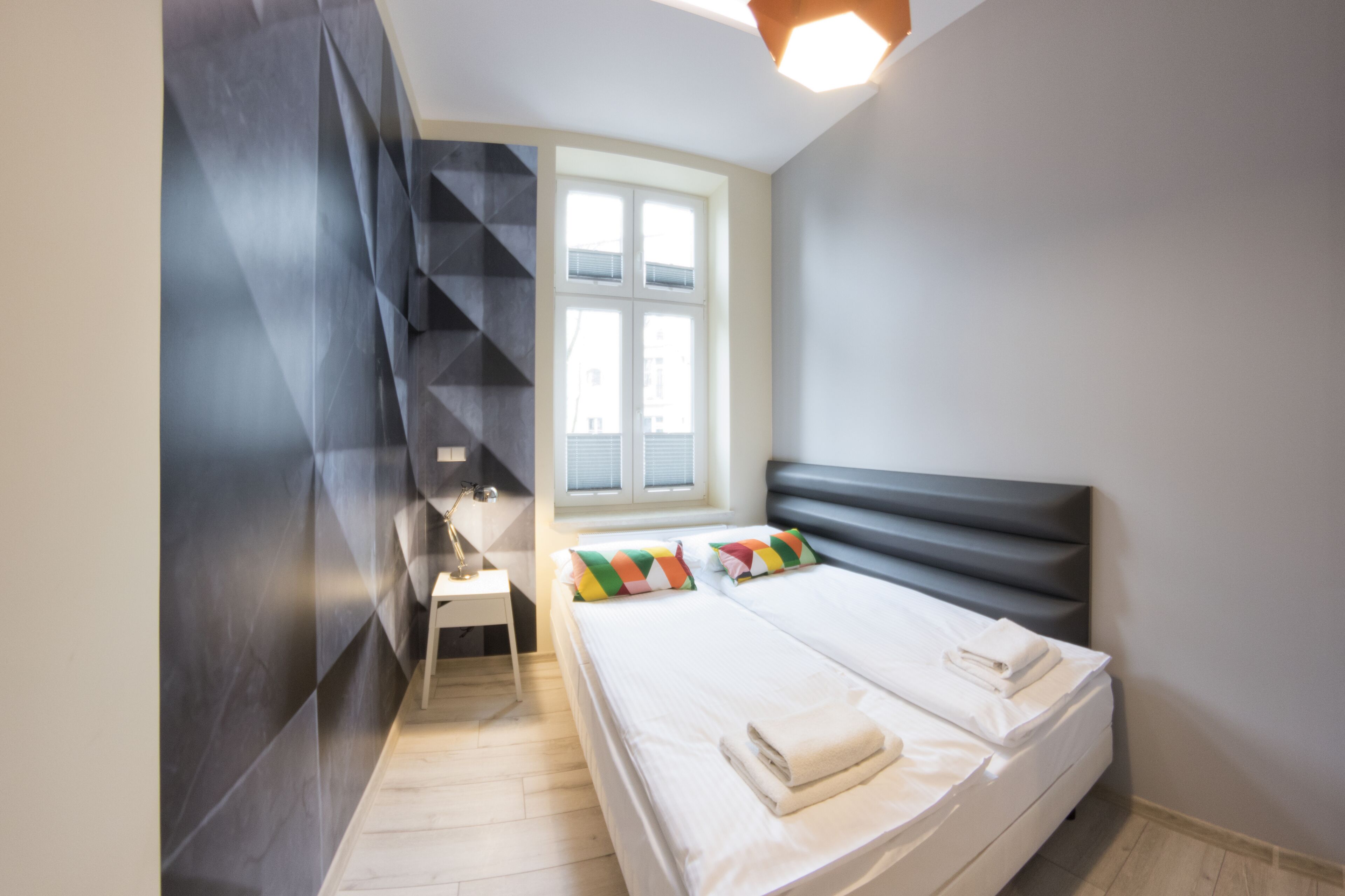 Een moderne slaapkamer met een bed, bureau en raam.