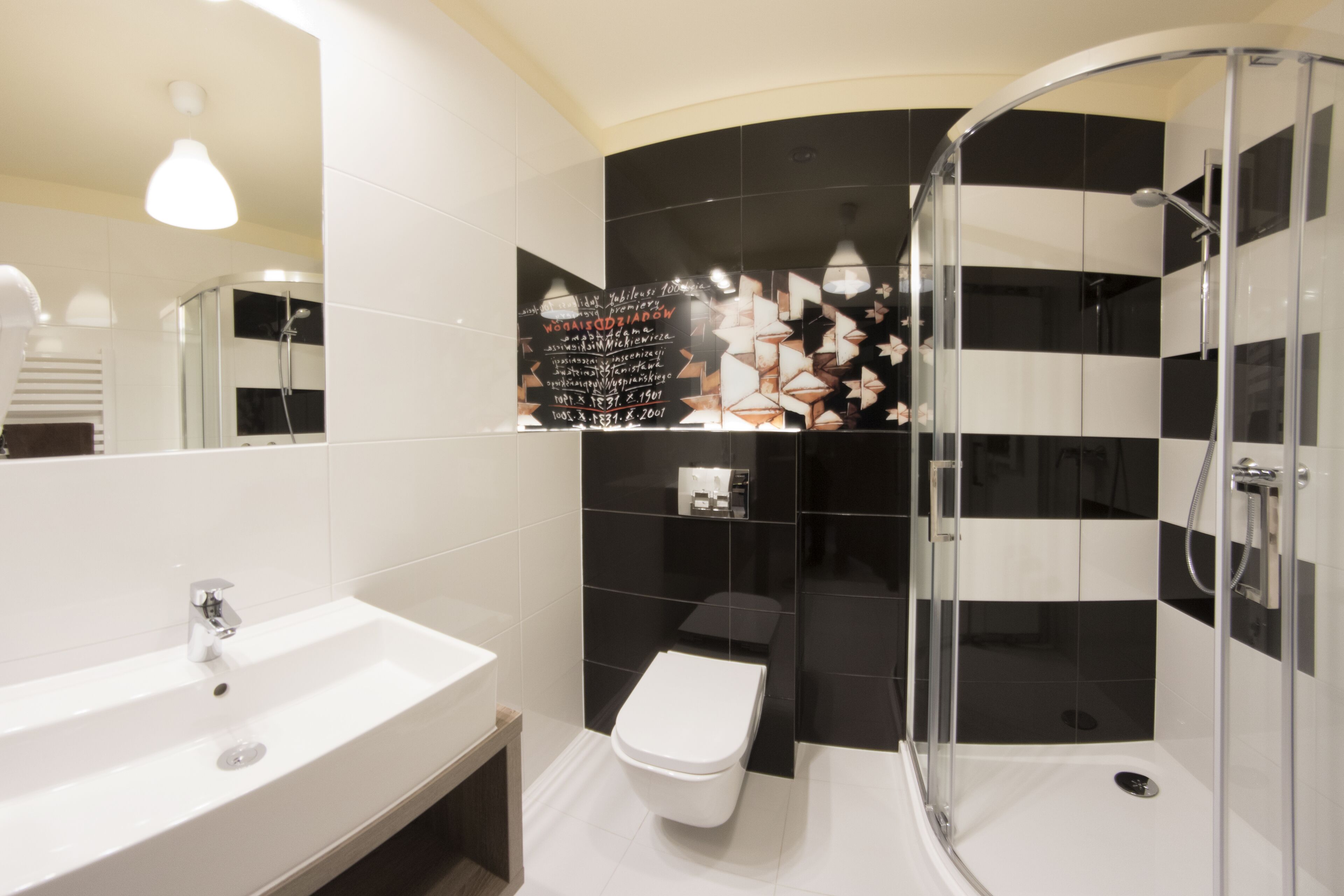 Et moderne badeværelse med en hvid vask, toilet og en bruseniche med glasvægge.