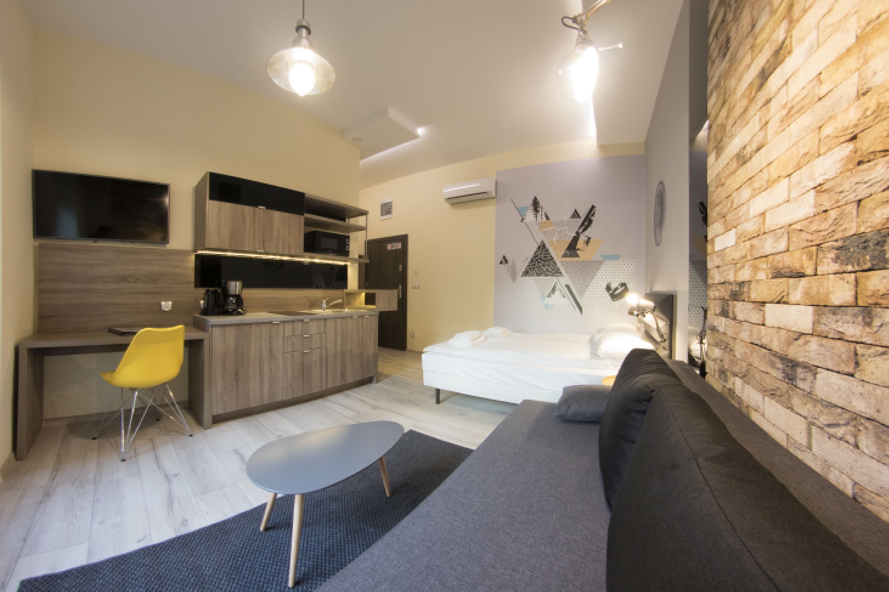 Espaço compacto com cozinha compacta, sofá, mesa de jantar e parede de tijolos decorativa.