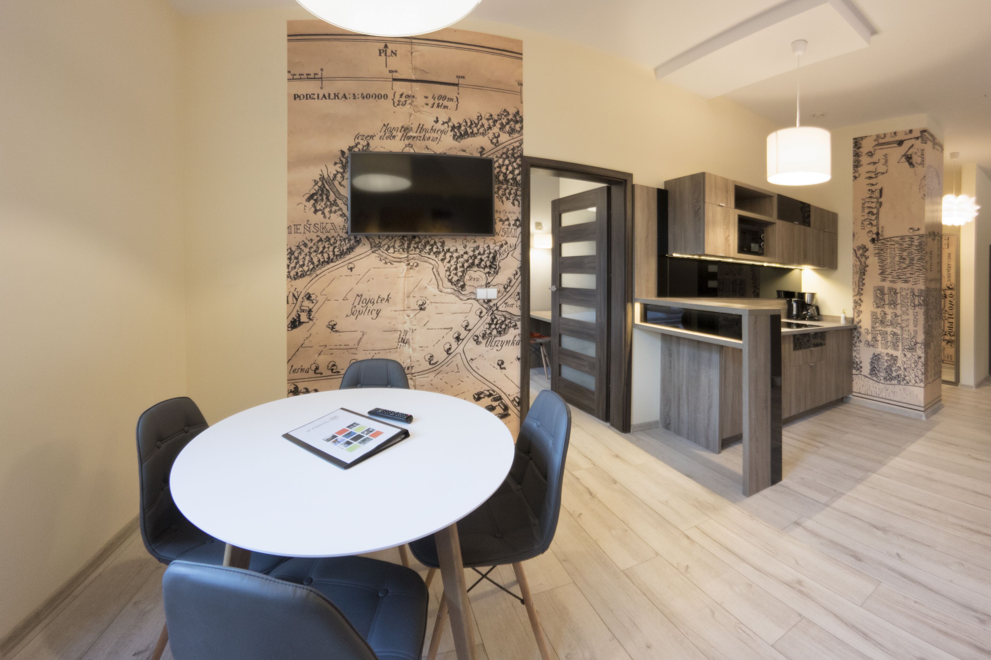 A modern kitchen with a built-in island, a dining area with a round table and chairs, and a map mural on the wall.