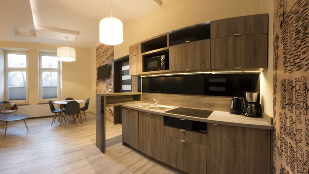 A modern kitchen with wooden cabinets, a built-in microwave, and a coffee maker. - Yourplace Central Apartments (Kraków)