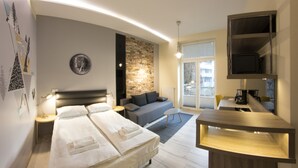 A modern hotel room with a large bed, a sofa, a desk, and a TV. - Yourplace Central Apartments (Kraków)
