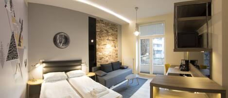 A modern hotel room with a large bed, a sofa, a desk, and a TV.
