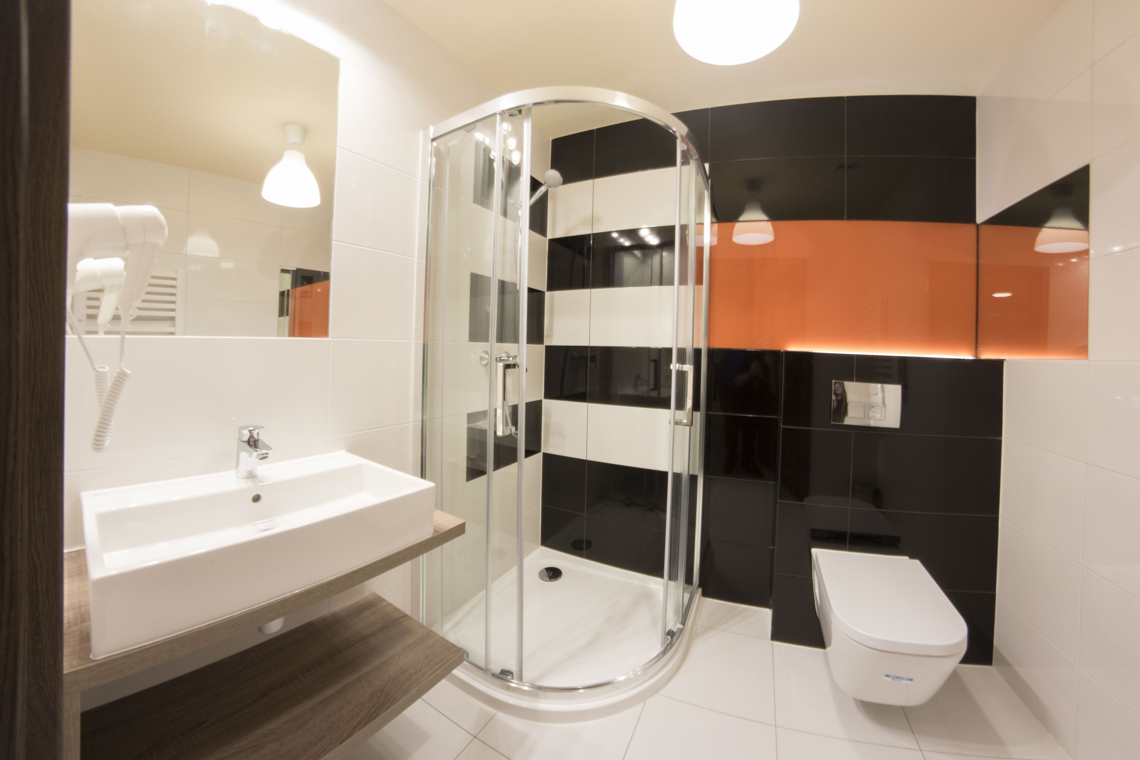 A modern bathroom with a glass-enclosed shower, a white sink, and a toilet.