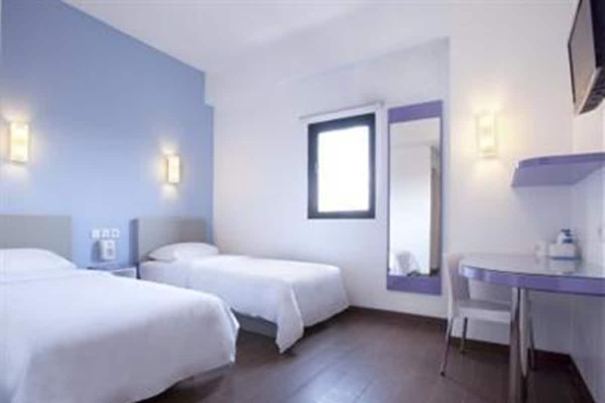 Ein Hotelzimmer mit zwei Betten, einem Schreibtisch und einem Spiegel.