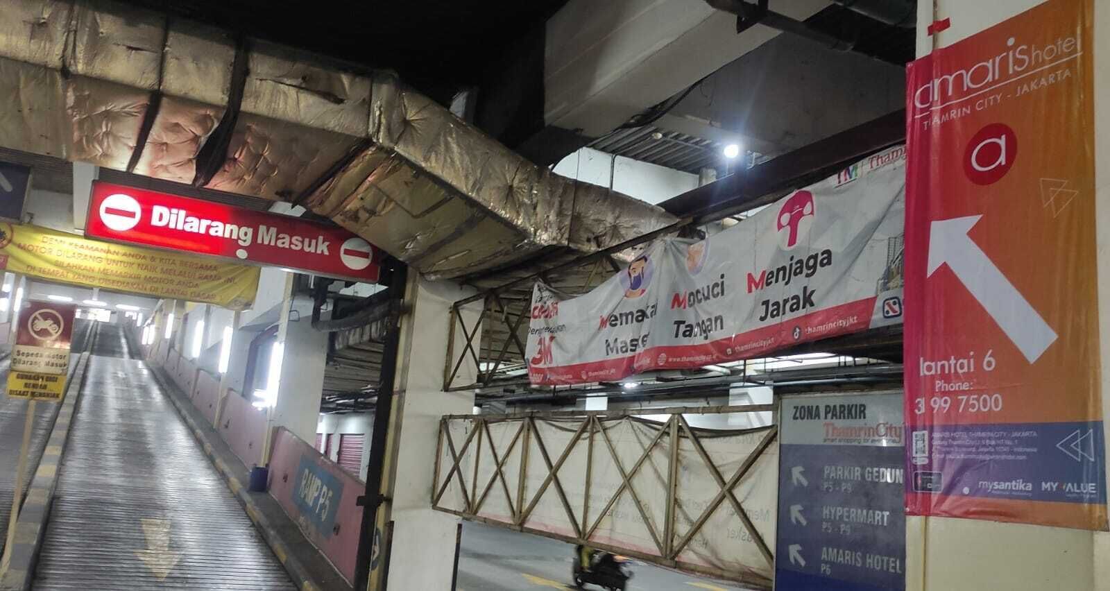 An indoor corridor with directional signs, a ramp, and a staircase.