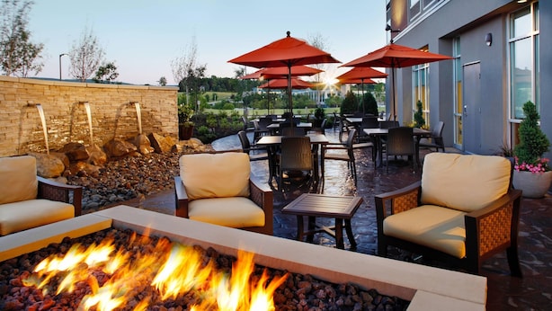An outdoor patio with a fire pit, seating, and umbrellas.