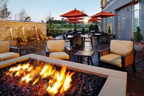 An outdoor patio with a fire pit, seating, and umbrellas. - SpringHill Suites Pittsburgh Latrobe (Latrobe)