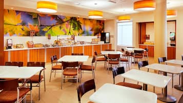 A restaurant with a counter, tables, and chairs.