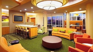 A modern hotel lobby with a bar, seating area, and a large window offering a view.