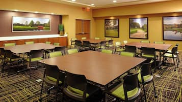 Una sala conferenze con diversi tavoli e sedie, un quadro di grandi dimensioni appeso al muro e un pavimento rivestito di moquette.
