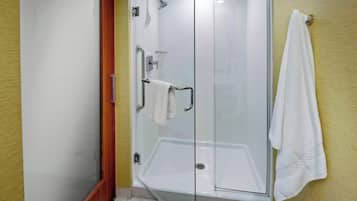 A glass-enclosed shower area with a white towel hanging on the wall.